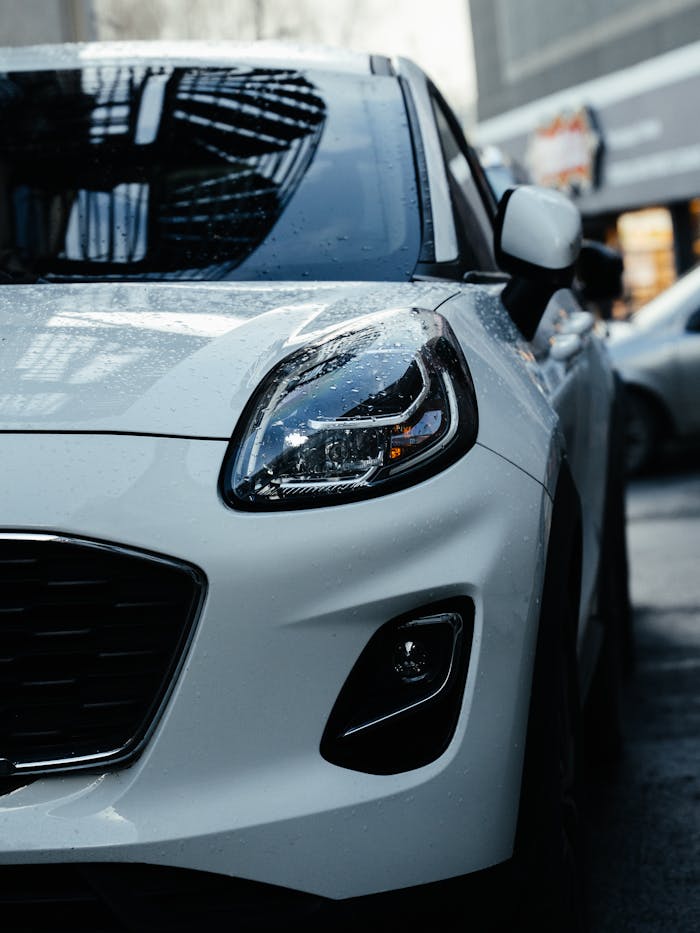 Close-up of a white car in an urban environment, showcasing its sleek design.